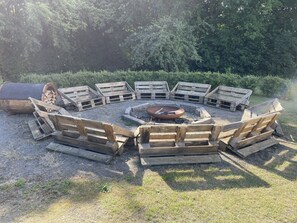 A circular fire pit surrounded by wooden benches in an outdoor setting.