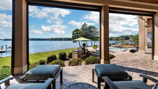 Une terrasse avec mobilier d’extérieur, une piscine et une vue sur un lac.