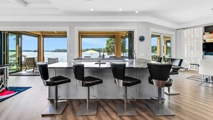 Une cuisine moderne dotée d’un grand îlot central, de tabourets de bar et offrant une vue sur l’eau.