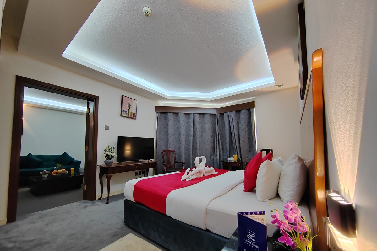 A hotel room with a bed, a desk, a television, and a seating area with a sofa and chairs.