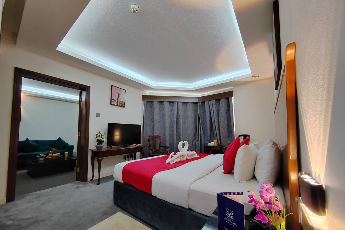 A hotel room with a bed, a desk, a television, and a seating area with a sofa and chairs.