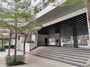 Step into a welcoming entrance with a covered area and metal canopy, surrounded by lush landscaping and a small tree.