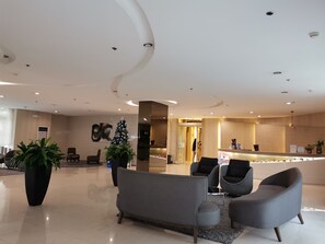 Relax in our welcoming lobby, featuring a reception desk, comfortable seating, and a lush potted plant.