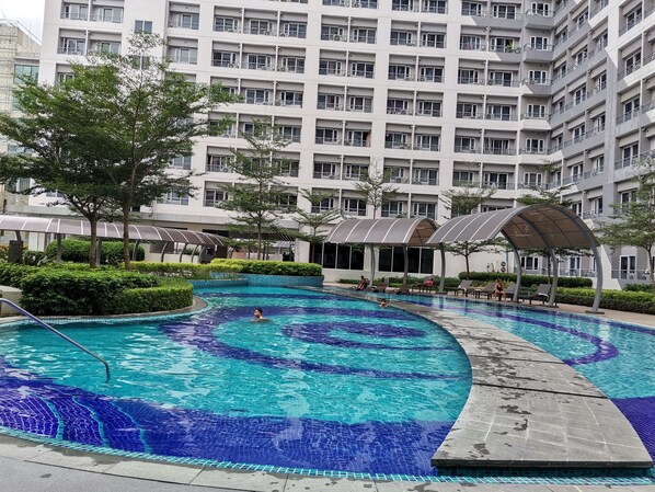 Enjoy a refreshing swim in the large circular pool surrounded by a beautifully maintained garden with hedges and trees.