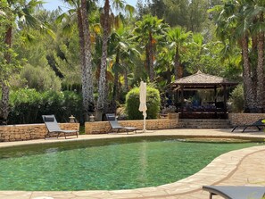 A pool area with lounge chairs, a gazebo, and palm trees. - Welcome to a place full of history and Mediterranean ease. (Sant Antoni)
