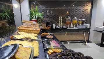 A buffet with various food items, including waffles, pastries, and a selection of fruits and vegetables.