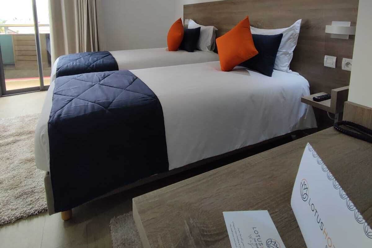 Habitación de hotel con una cama grande, un escritorio con silla, una ventana con cortinas y un cuadro en la pared.
