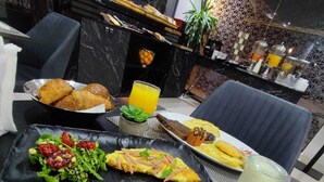Une table dressée pour le petit-déjeuner avec des croissants, une salade et une assiette de fruits.