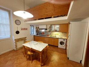 A compact kitchen with wooden cabinets, a built-in washing machine, and a dining table with chairs. - Entire apartment fully equipped. Ideal for families or for work. (Palermo)