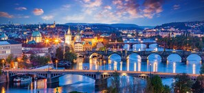 A cityscape with a prominent bridge, historic buildings, and a river reflecting city lights. - 3-bedrooms apartment in center of Prague (Prague)