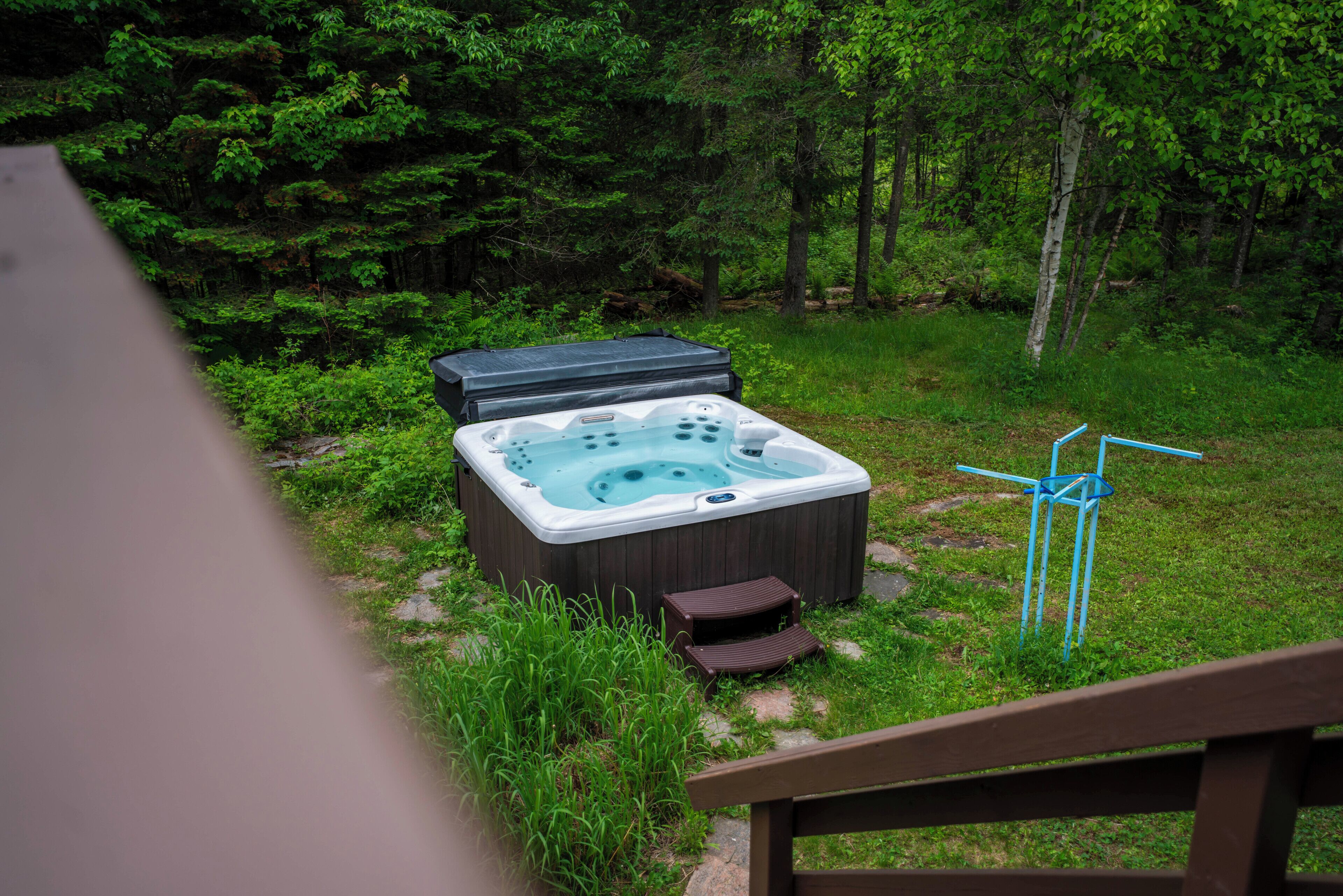 A hot tub in a forested area with a wooden deck in the foreground.
