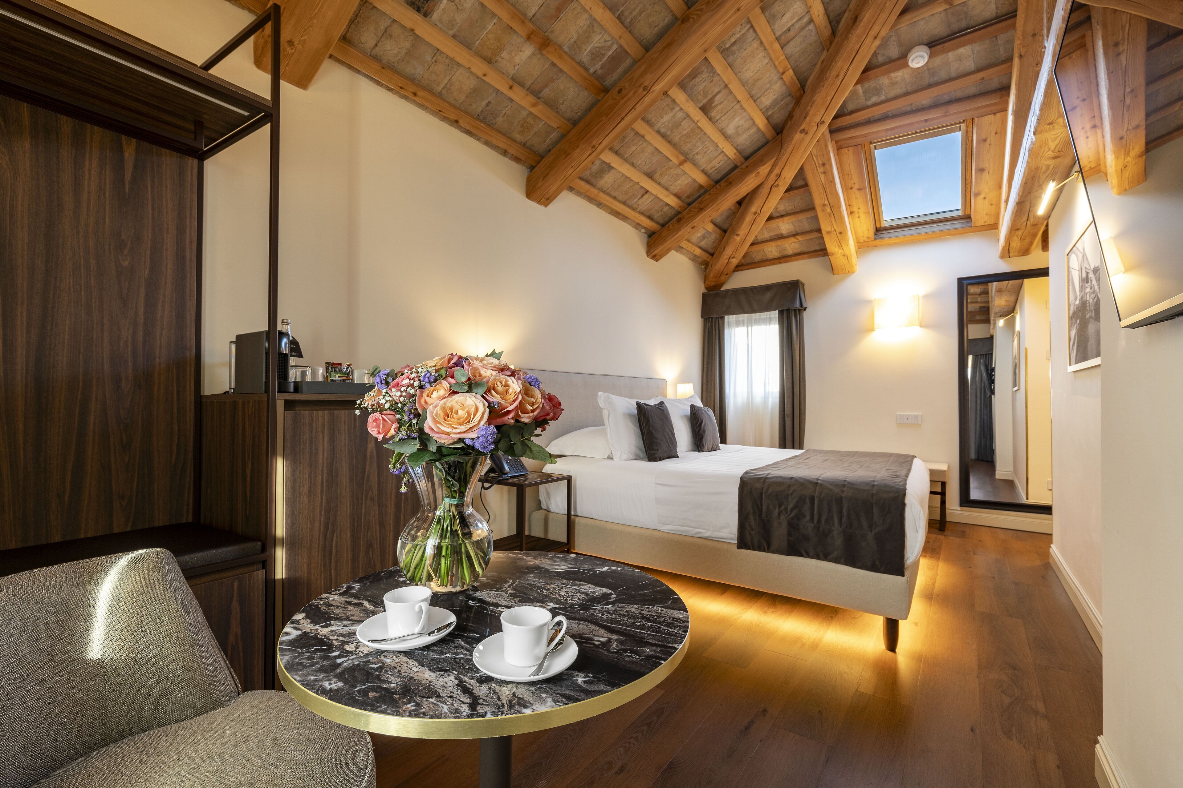 Un dormitorio con cama, mesita de noche y ventana, con vistas al cielo.