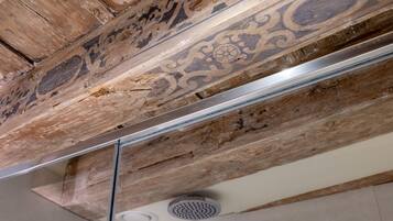 A ceiling with exposed wooden beams and a modern light fixture.