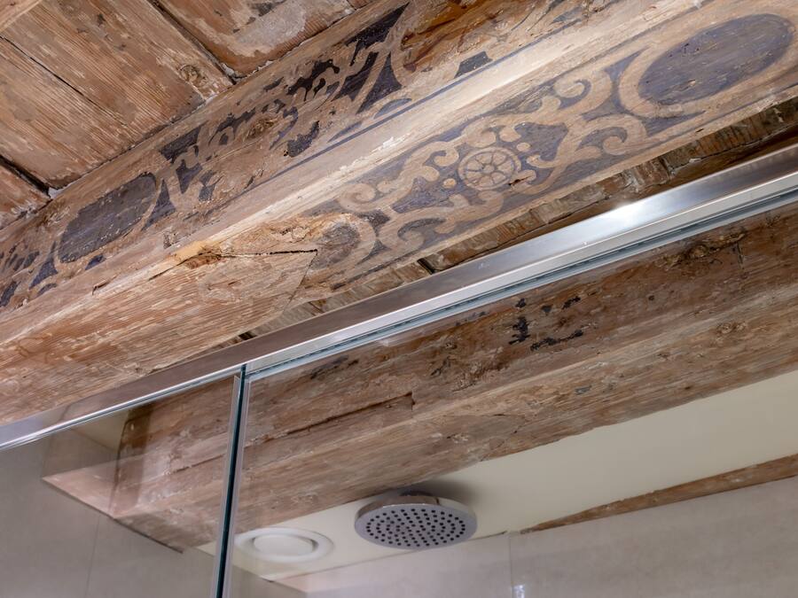A ceiling with exposed wooden beams and a modern light fixture.