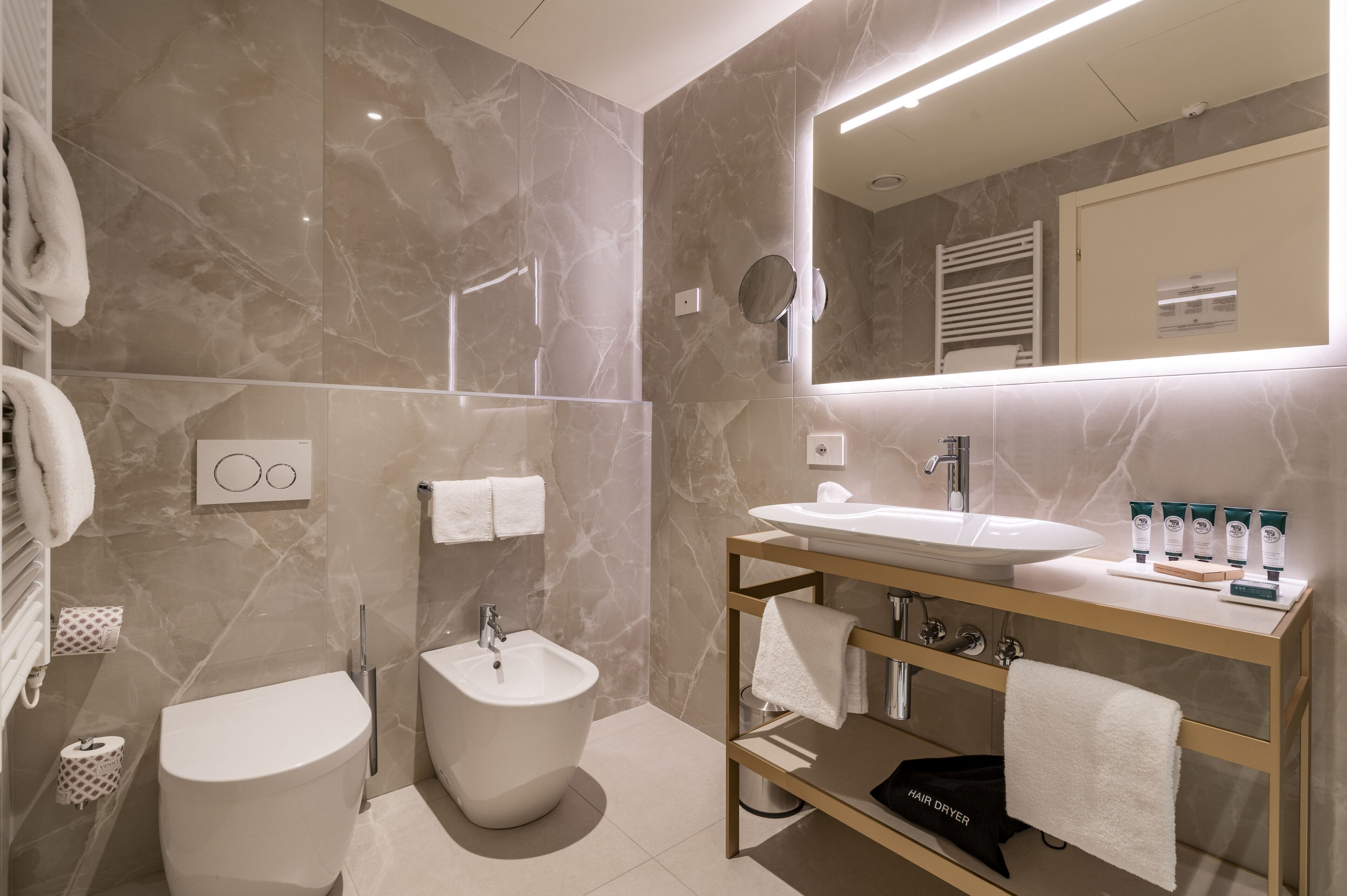 A modern bathroom with a bidet, toilet, sink, and vanity.