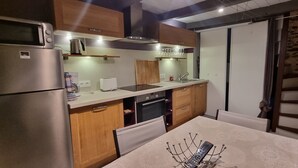 Una cocina compacta con electrodomésticos de acero inoxidable, armarios de madera y un comedor con mesa y sillas.