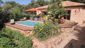 A pool area with a wooden deck, lounge chairs, and a covered seating area. - VILLA LA TREILLE (Saint-Maximin-la-Sainte-Baume)