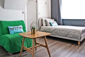 A modern room with a green sofa, a grey sofa, a wooden table, and a grey bed.
