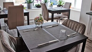 Zona pranzo con tavolo apparecchiato per quattro persone, inclusi un vaso con fiori, un bicchiere d'acqua e posate.