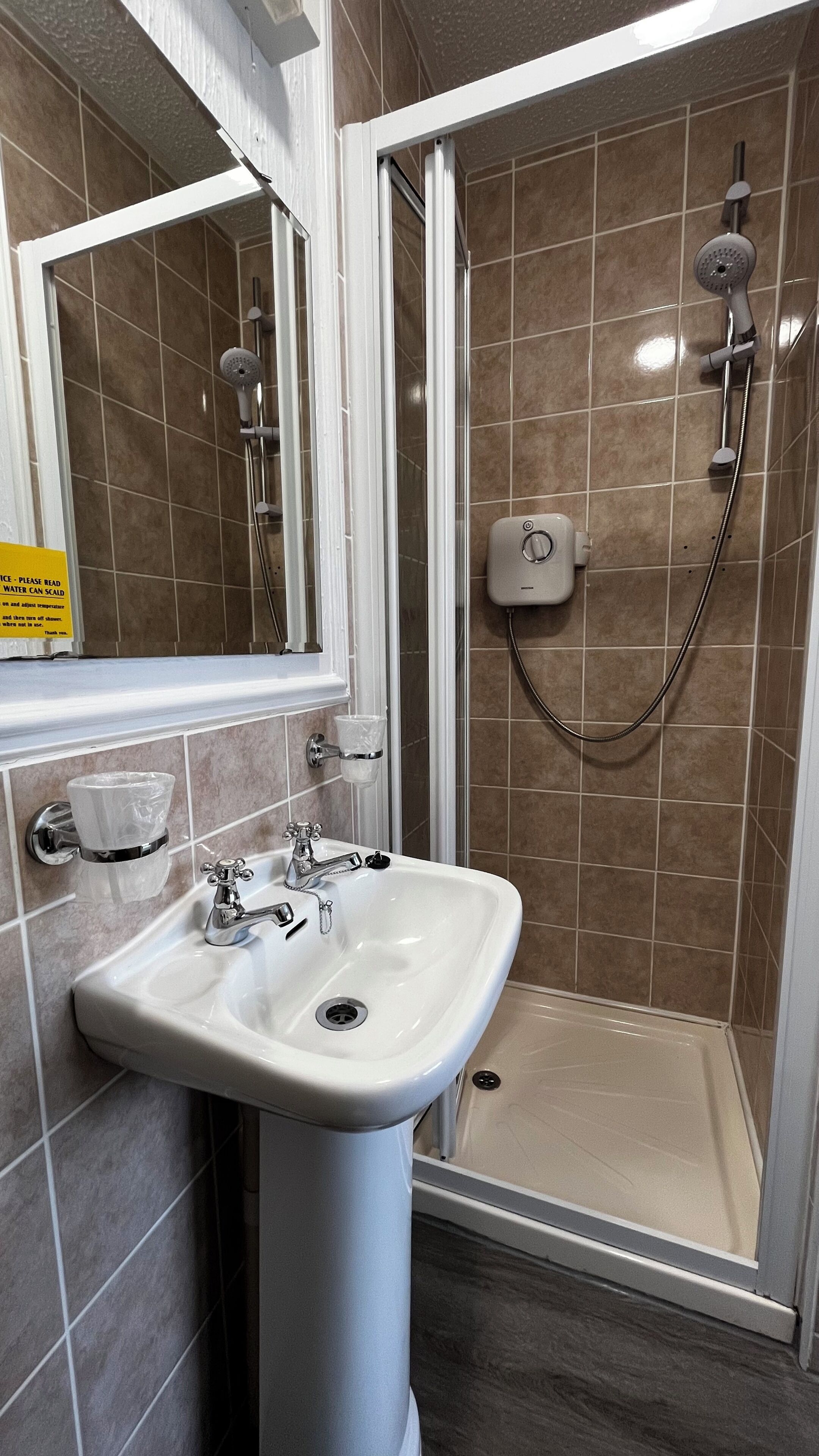 Ein Badezimmer mit Dusche, Waschbecken und Spiegel.