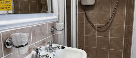 Ein Badezimmer mit Dusche, Waschbecken und Spiegel.