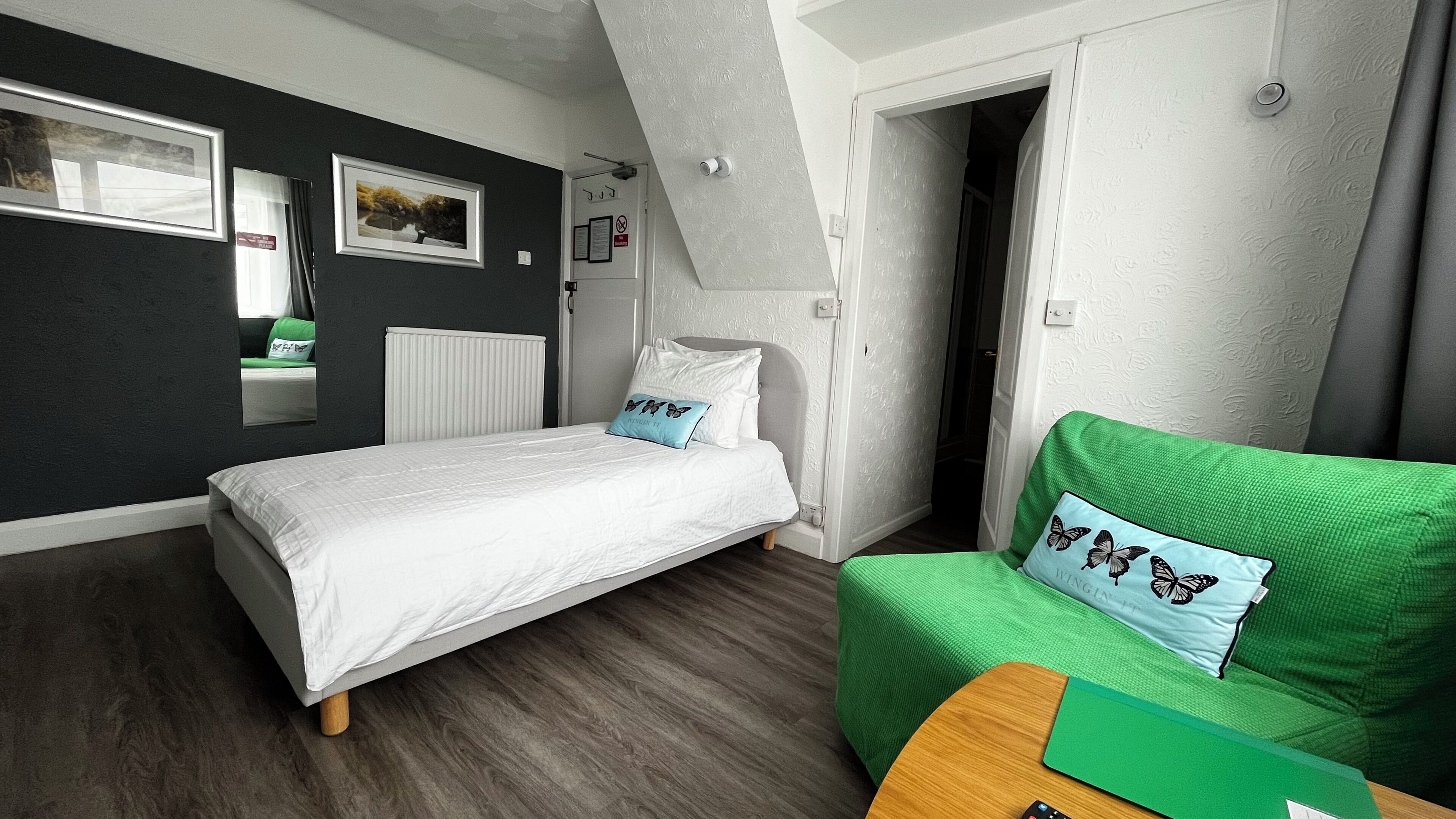 A bedroom with a bed, a green chair, a radiator, and a window.