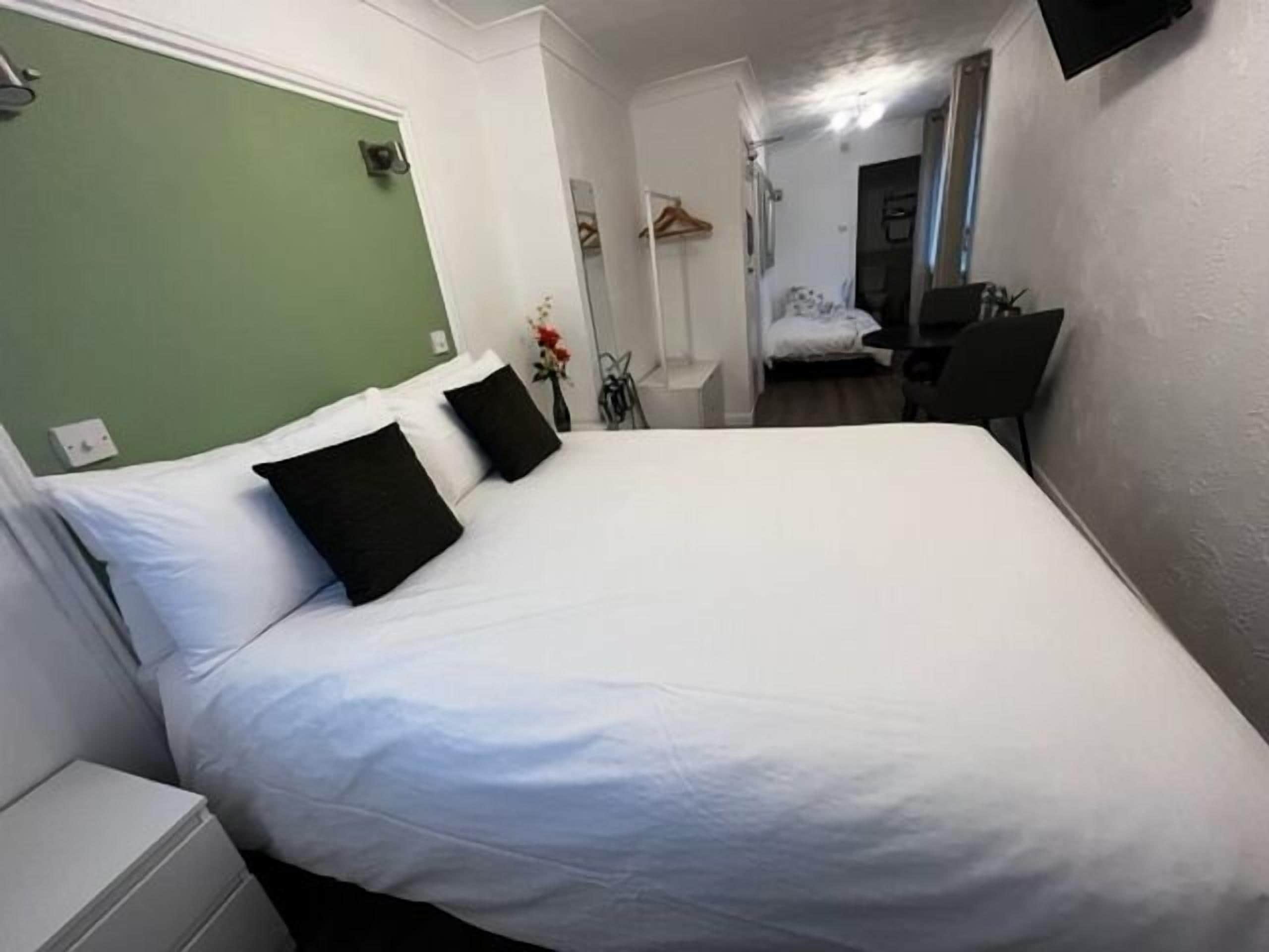 Una habitación de hotel con una cama grande, una mesita de noche, una silla y un escritorio.
