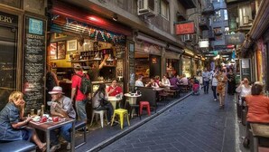 Eine schmale Straße mit Außenbestuhlung mehrerer Cafés und Restaurants.