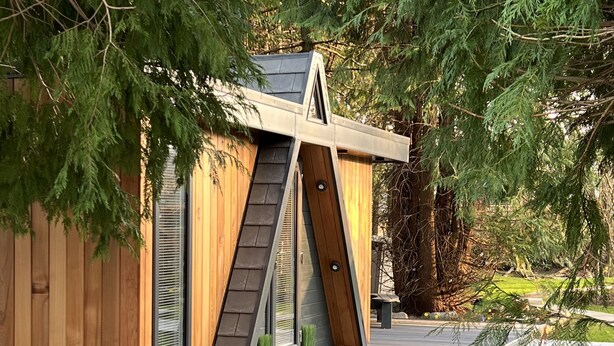 A wooden cabin with a sloped roof, a small porch, and a caution sign on the door. - Royal Snug & WEE Snug (Aboyne)
