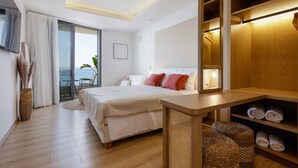 Ein modernes Schlafzimmer mit einem großen Bett, einem Holzschrank und Meerblick durch die Glastür.