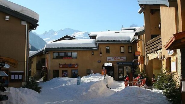 A snow-covered street with buildings, including a visible sign for 'Petit P'tit'.