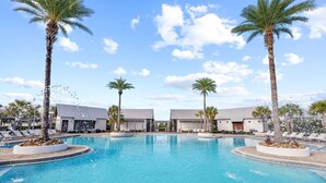 Piscina cercada por palmeiras e cadeiras de sol, com edifícios de design moderno.