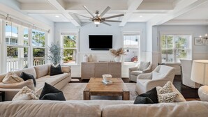 A spacious living room with a ceiling fan, large windows, a flat-screen TV, and a comfortable seating area. - ☀️ 6 Beds | Golf Cart | Near Beach (Santa Rosa Beach)