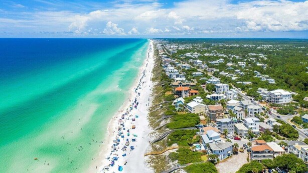 An aerial view of a coastal area with a long sandy beach, numerous buildings, and a clear blue sky. - ☀️ 6 Beds | Golf Cart | Near Beach (Santa Rosa Beach)
