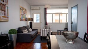 A living room with a sofa, a striped chair, a metal bowl, and a potted plant. - Maison Moz - Moldarte (Maputo)