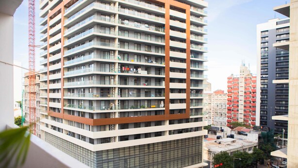 A high-rise building with multiple balconies, large windows, and a construction crane in the background. - Maison Moz - Moldarte (Maputo)