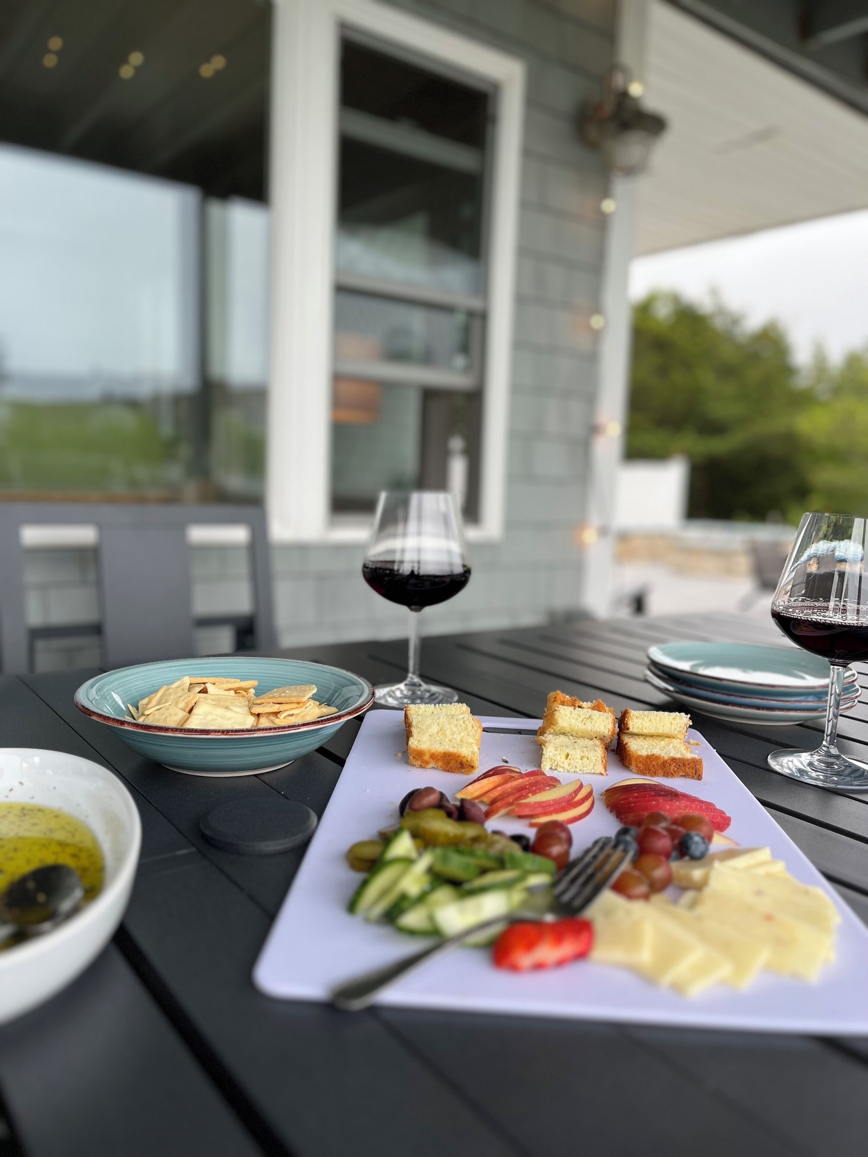 Ein Esstisch mit einer Auswahl an Speisen, darunter Brot, Käse und Obst, sowie zwei Gläsern Rotwein.