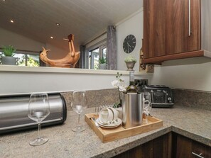 A kitchen with granite countertops, a wooden cabinet, a clock, and a decorative bird sculpture.