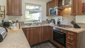 Une cuisine moderne avec des meubles en bois, un évier en acier inoxydable, un four à micro-ondes encastré et une cuisinière à gaz.