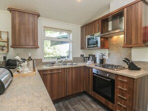 A modern kitchen with wooden cabinets, a stainless steel sink, a built-in microwave, and a gas stove.