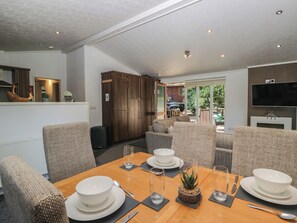 A modern dining area with a wooden table set for four, surrounded by comfortable seating.