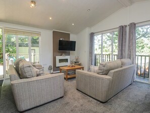A living room with two sofas, a coffee table, and a flat-screen TV mounted above a fireplace.
