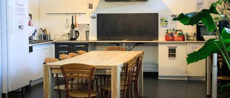 Una cocina moderna con una mesa y sillas de madera, una campana extractora de acero inoxidable y una pizarra en la pared.
