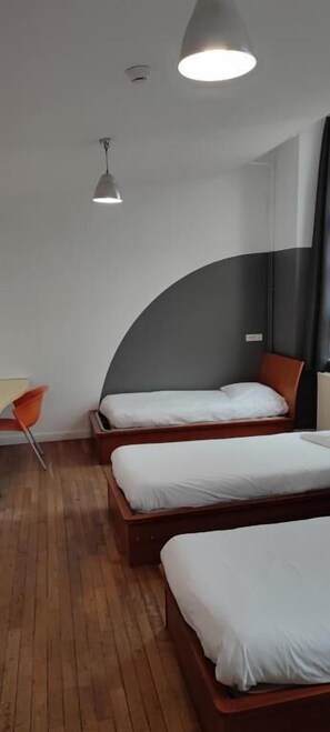 A room with three wooden beds, a round ceiling light, and a modern chair. - Auberge de Jeunesse HI Amiens (Amiens)