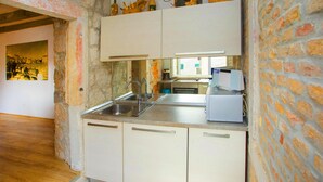 Una cocina con armarios blancos, un lavamanos de acero inoxidable y una ventana.