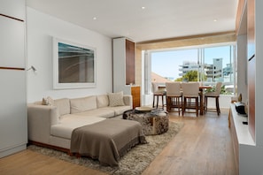 A modern living room with a sofa, ottoman, and dining area. - Stunning Bantry Bay Haven - Beach on Your Doorstep (Cape Town)