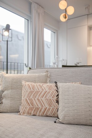 A modern living room with a sofa set, patterned cushions, and a floor lamp. - Liiiving - Modern & Glam Apartment M (Porto)