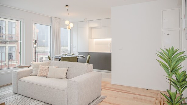A modern living room with a sofa, a dining table, and a kitchen area. - Liiiving - Modern & Glam Apartment M (Porto)