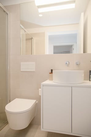 A modern bathroom with a toilet, sink, and shower. - Liiiving - Modern & Glam Apartment M (Porto)