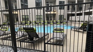 Un área de piscina con sillones de descanso y una valla.